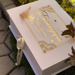 Christening box with gold text and ecru ribbon on a natural background
