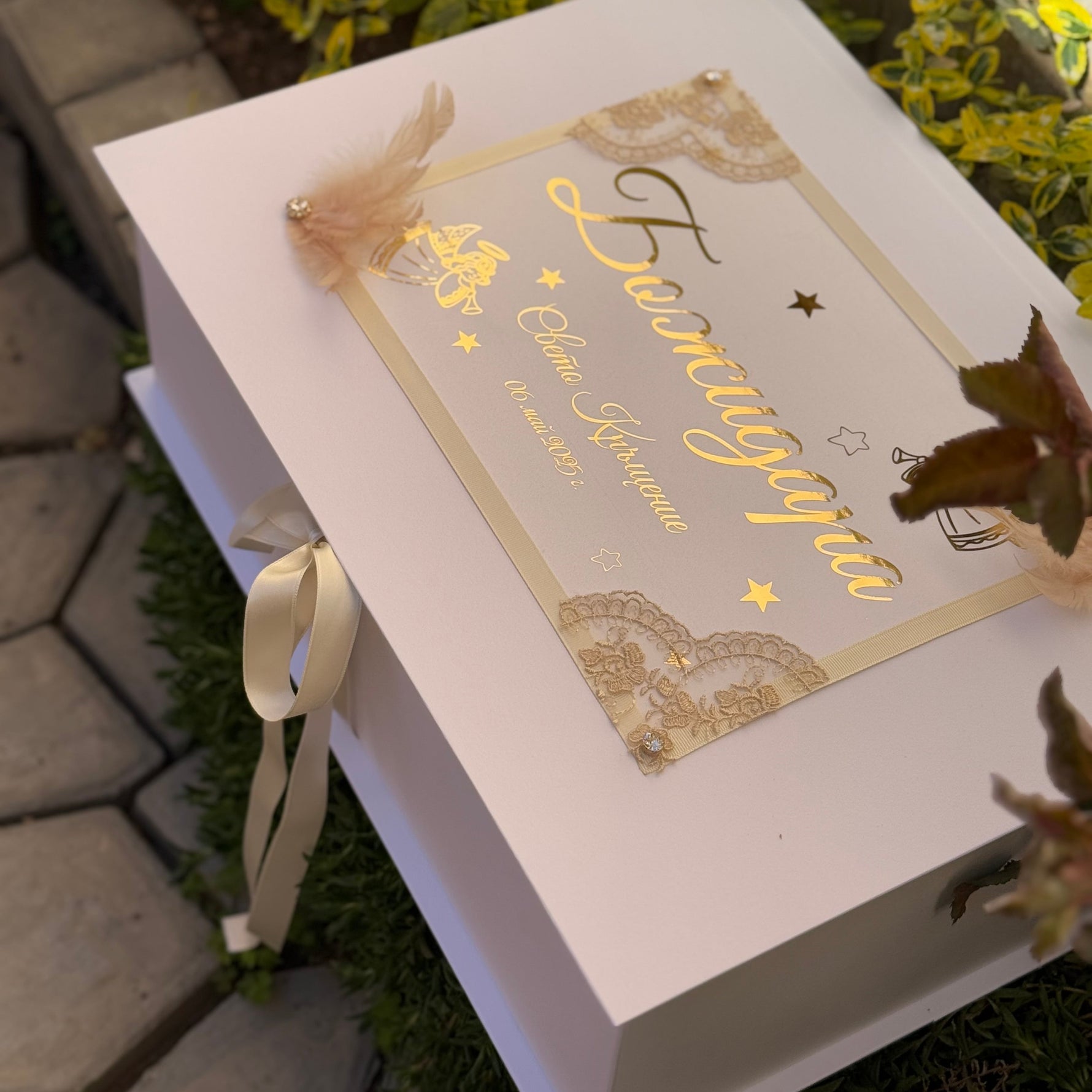 Christening box with gold text and ecru ribbon on a natural background