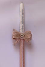 Decorative candle with pink lace bow and pearl embellishments on a light background