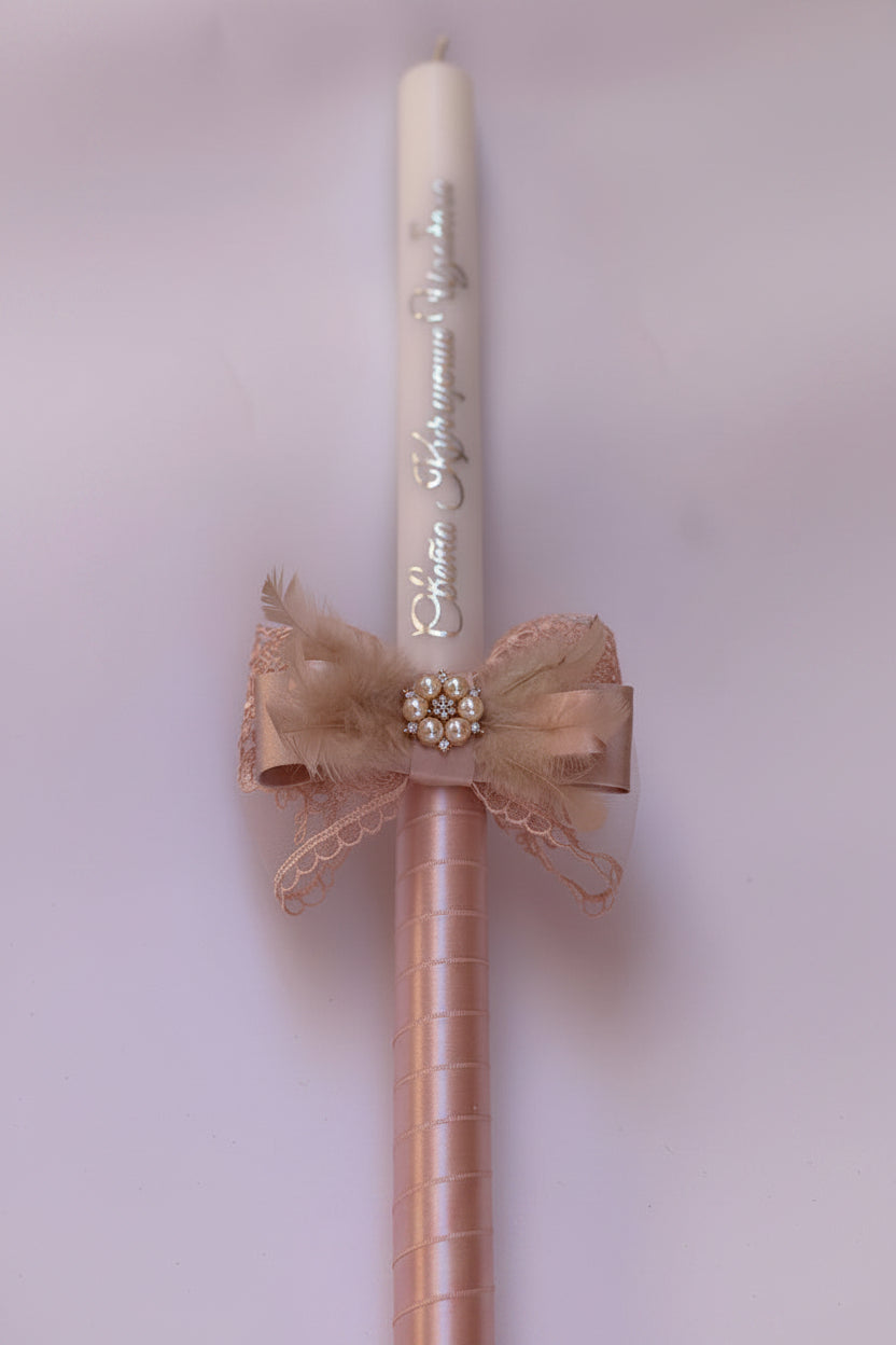 Decorative candle with pink lace bow and pearl embellishments on a light background