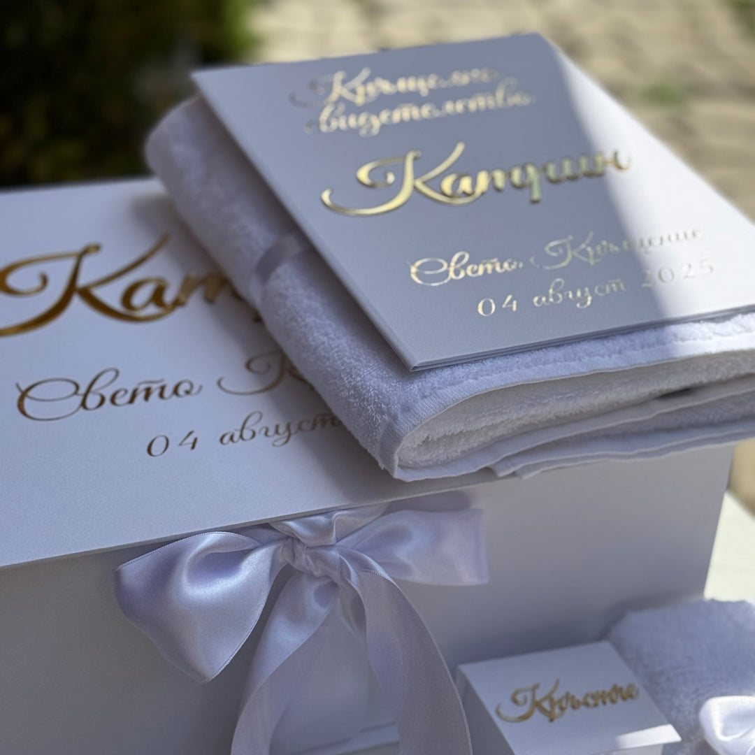 Decorative box with a white ribbon and gold text on a blurred background