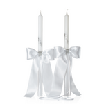 Two white wedding orthodox candles with satin ribbons and decorative elements on a white background