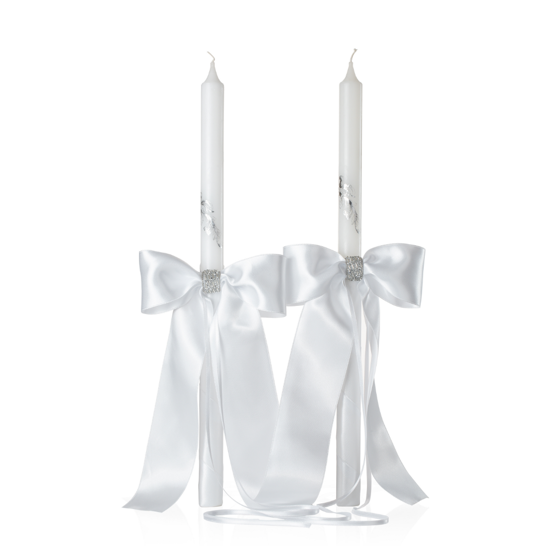 Two white wedding orthodox candles with satin ribbons and decorative elements on a white background