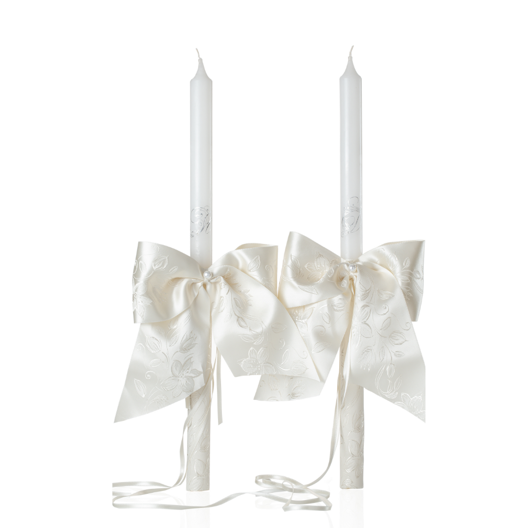 Two white candles with decorative ECRU bows on a white background