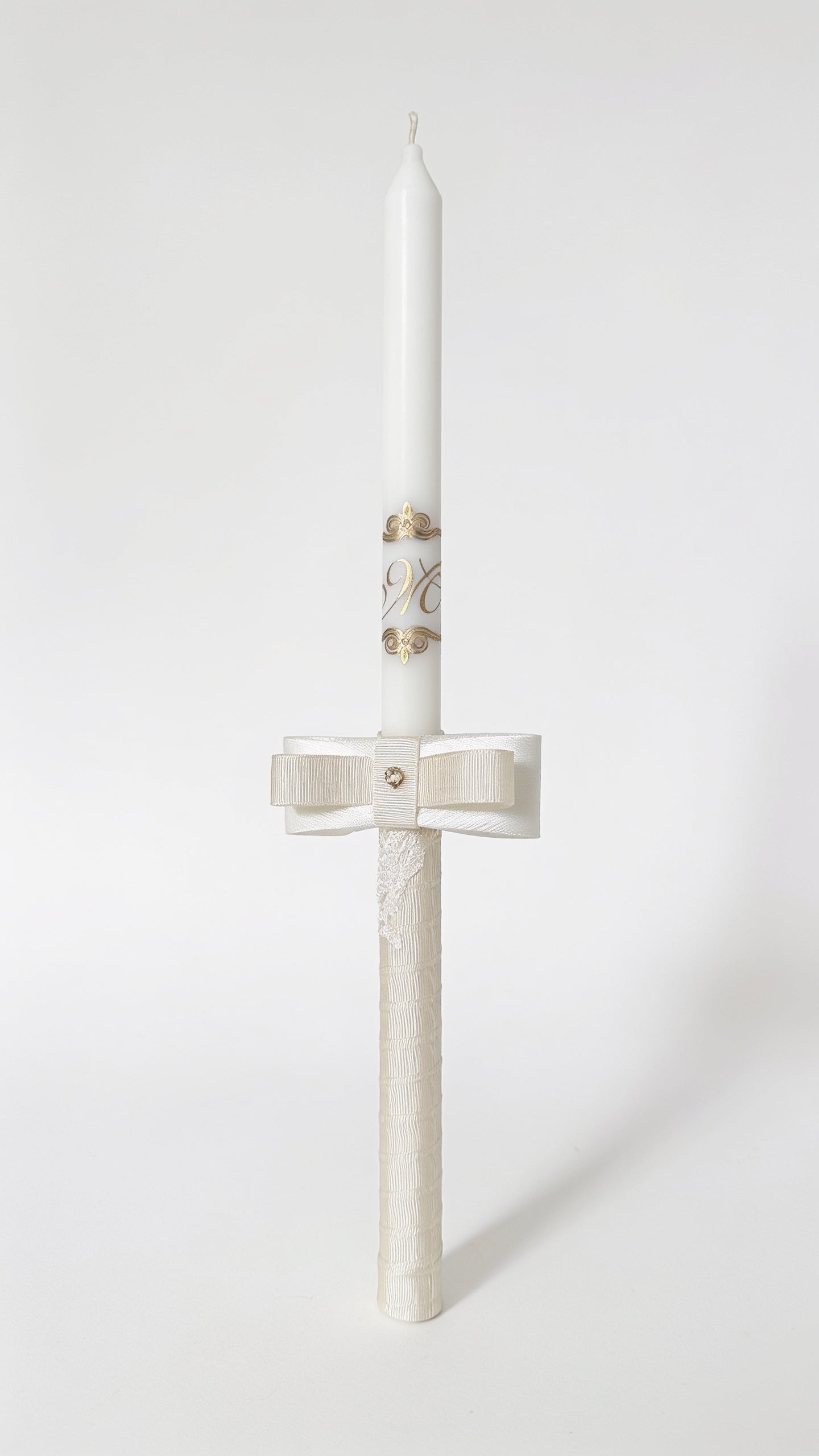 Handmade personalised ecru baptism candle with elegant layered bow and lace details.