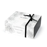 Candle box with floral design and black ribbon on a white background