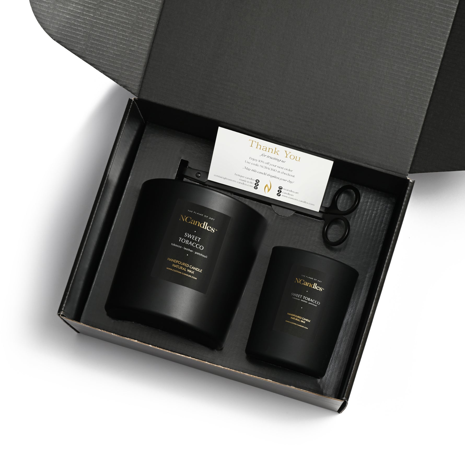 Two black candles in a gift box with a 'Thank You' card and scissors.