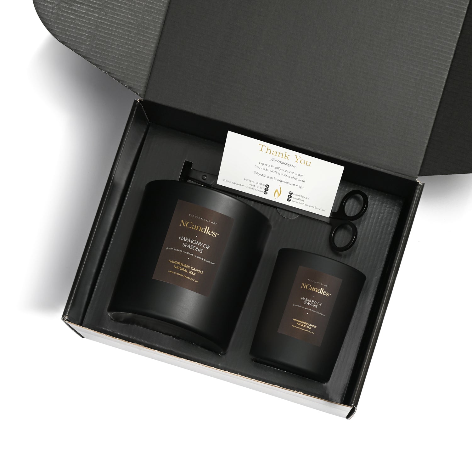 Two black candles in a box with a card and scissors, featuring the brand 'NCandle'.