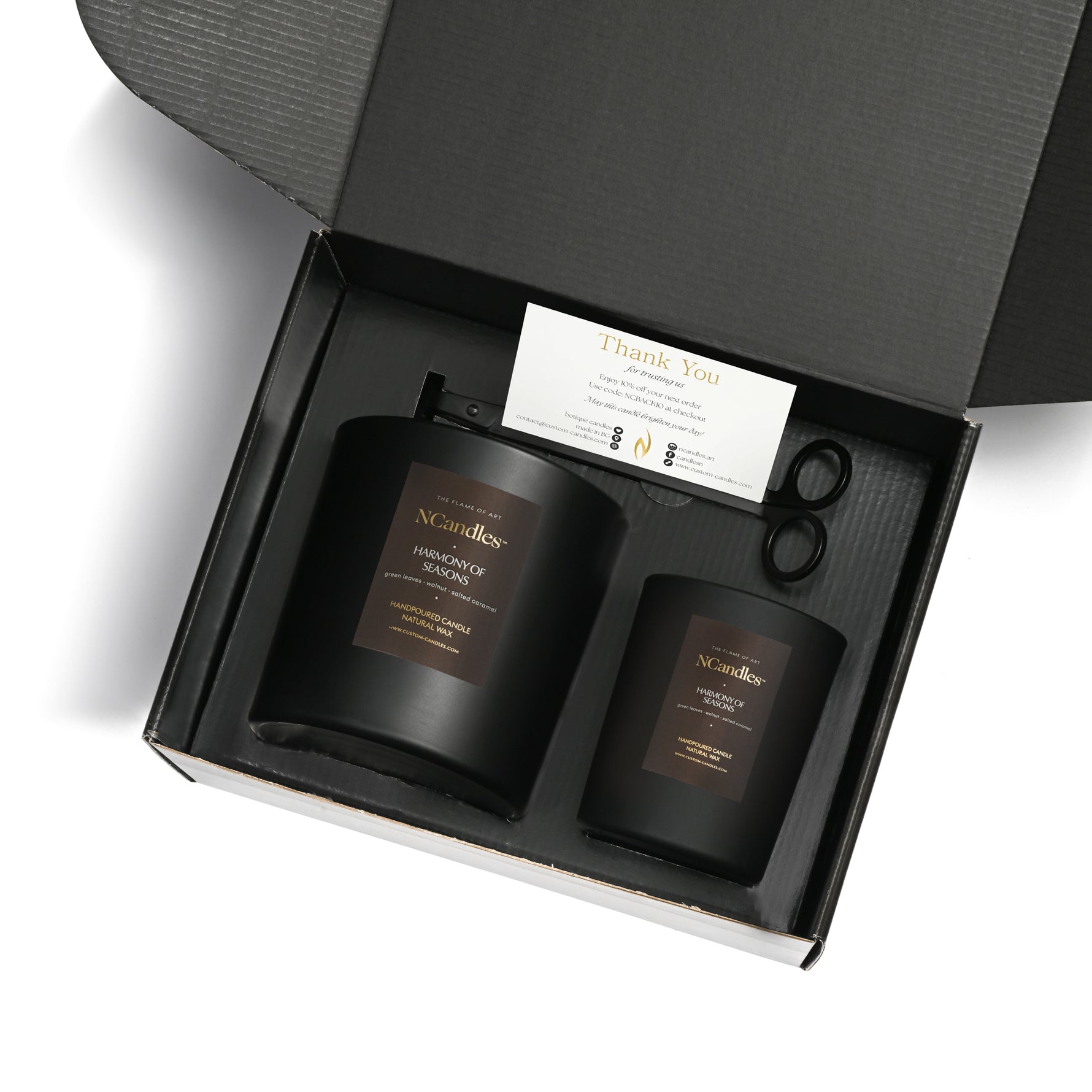 Two black candles in a box with a card and scissors, featuring the brand 'NCandle'.