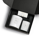 black box with 2 sized candles in white matt vessels 